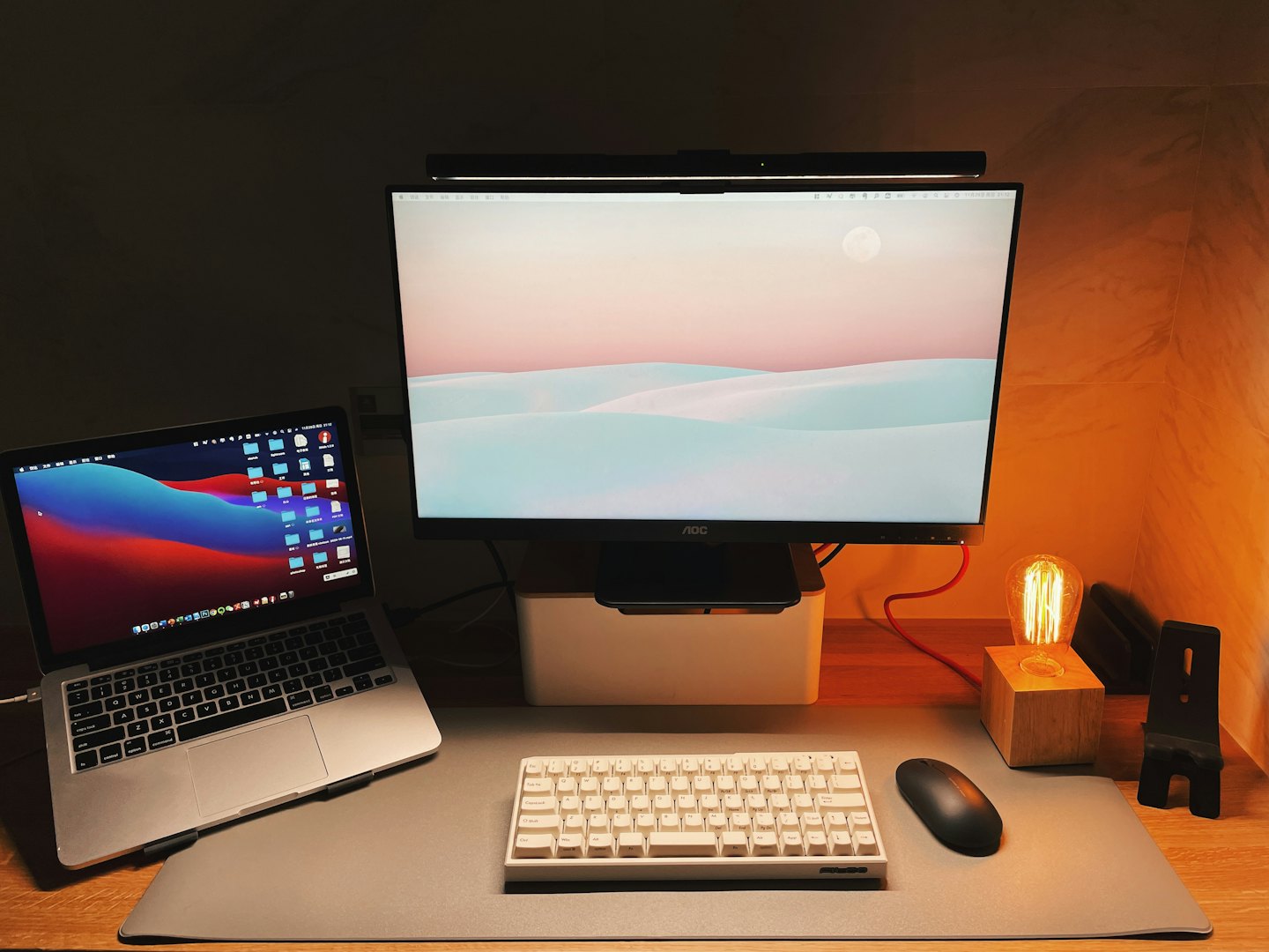 Un laptop e un monitor siedono su una scrivania di legno.